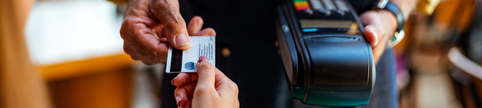 Close up of two people's hands exchanging a credit card