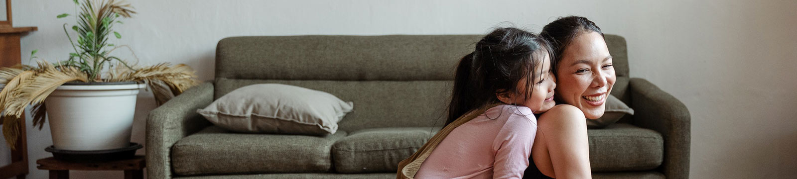 A mother and young daughter doing yoga in a living room